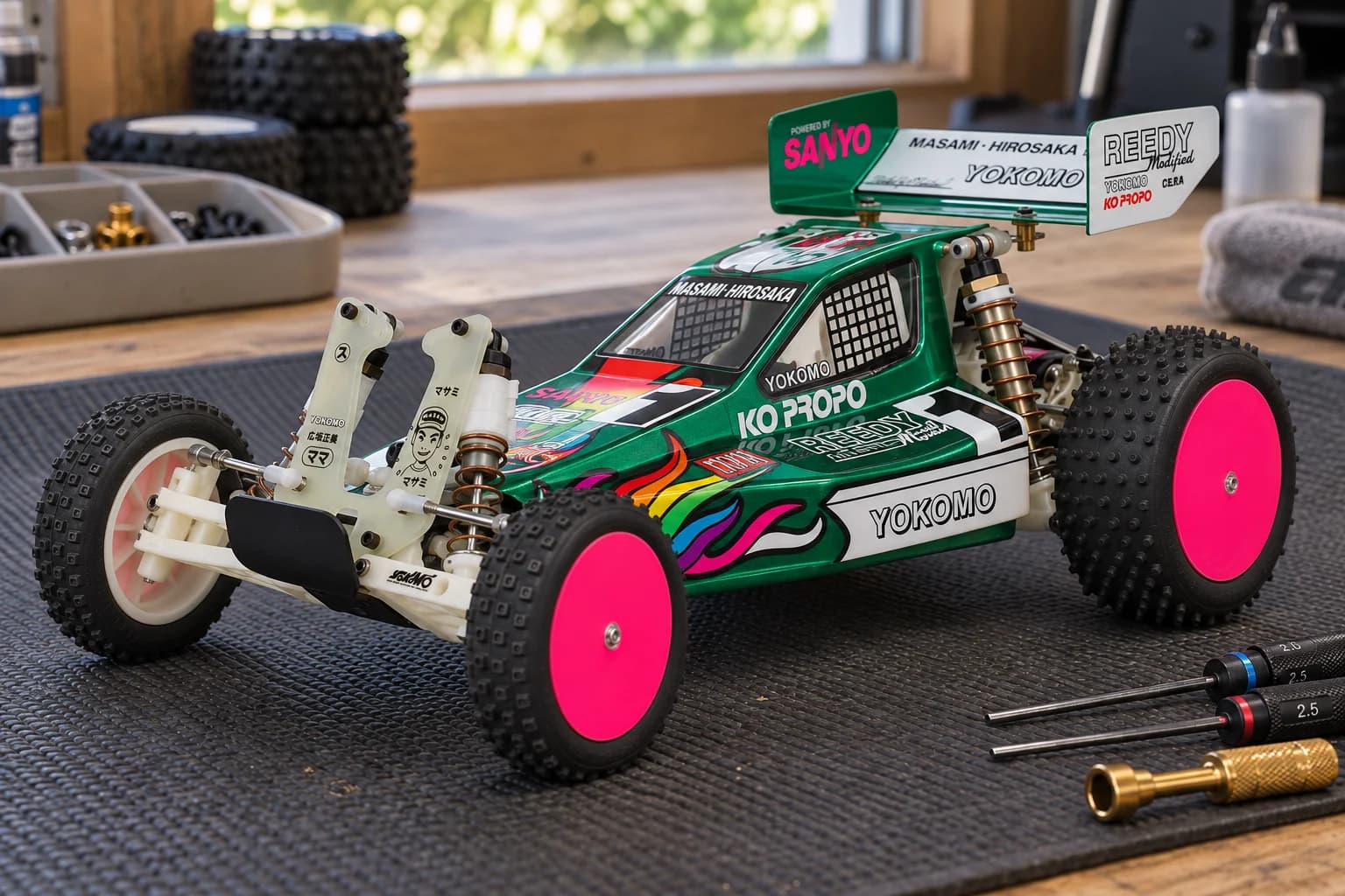 A metallic green Team Associated RC10 1991 Stealth Masami with pink wheel faces on a workshop mat