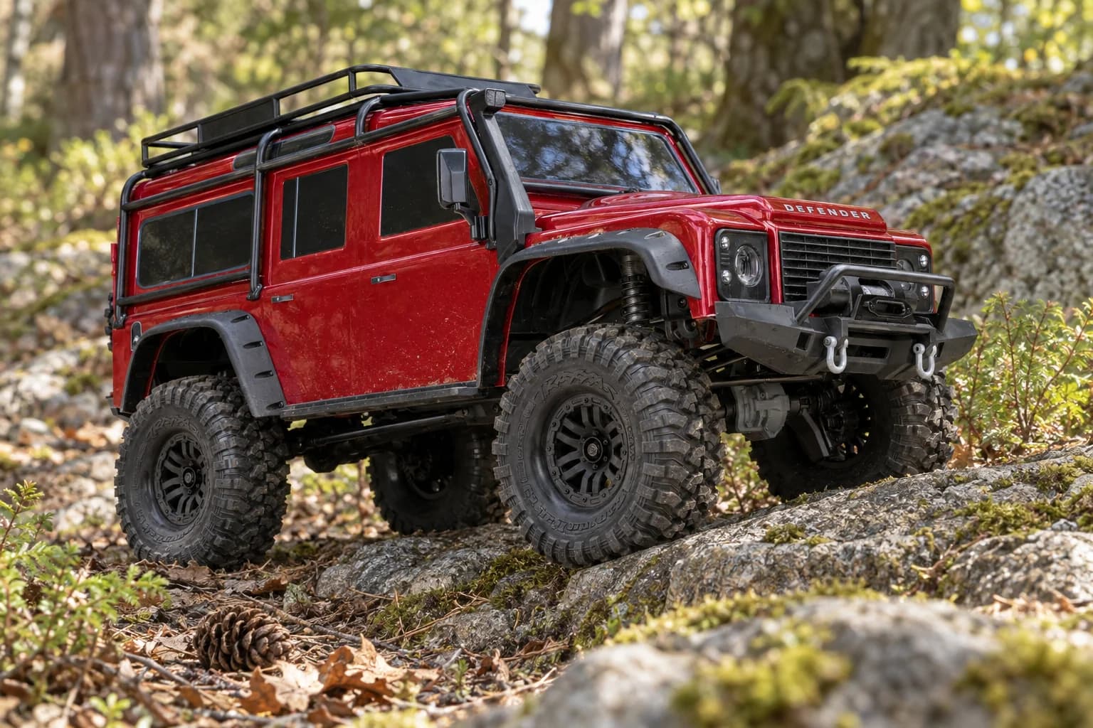 A red Traxxas TRX-4 Defender climbing over mossy rocks on a woodland trail